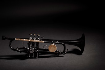 caption: The Instrument of Hope is lacquered in black except for the shiny brass parts, which are clear lacquered. They include the lead pipe, which is made from bullets set end to end and drilled out so that air can flow through to make it a playable instrument. The tops of the three buttons are made of the sawn-off casing end caps or rims.