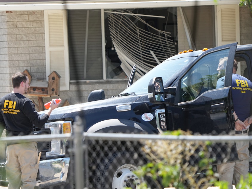 caption: FBI agents process the home of Craig Robertson who was shot and killed by the FBI in a raid on his home on Wednesday in Provo, Utah. The FBI was investigating alleged threats by Robertson to President Biden ahead of the president's visit to the state this week.