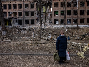 caption: A woman stands in front of a destroyed building after a Russian missile attack in the town of Vasylkiv, near Kyiv, on  Sunday. Russian forces faced stiff resistance over the weekend and faced logistics problems in their invasion plans.