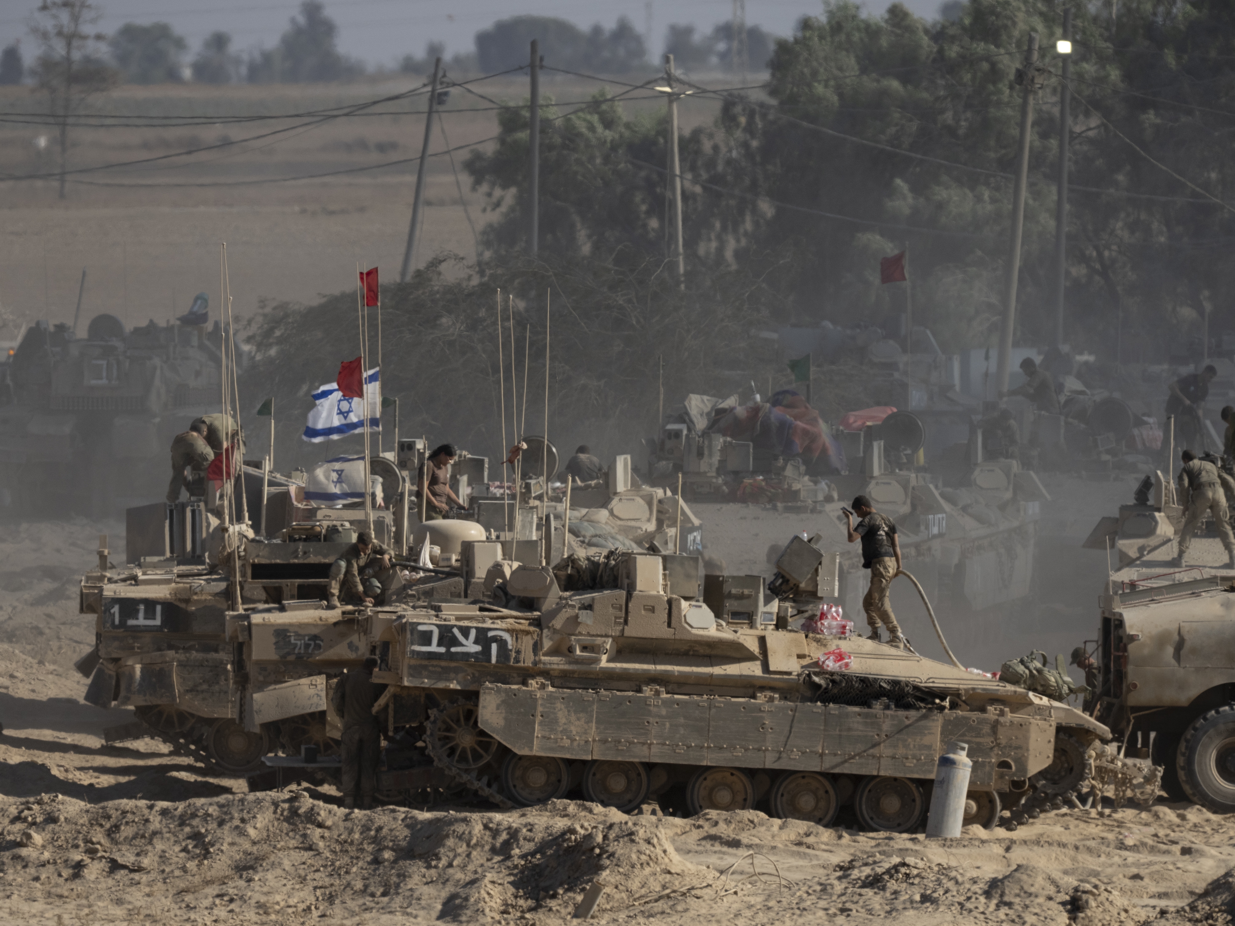 caption: Israeli soldiers organize military equipment while standing on armored personnel carriers near the border with the Gaza Strip on Wednesday in southern Israel.