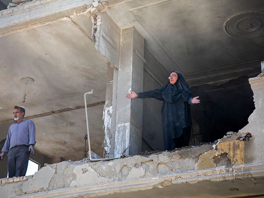 caption: A resident gestures from an upper floor of a ruined residential building that was hit in an airstrike earlier this morning on March 30, 2026 in the west of Tehran, Iran.