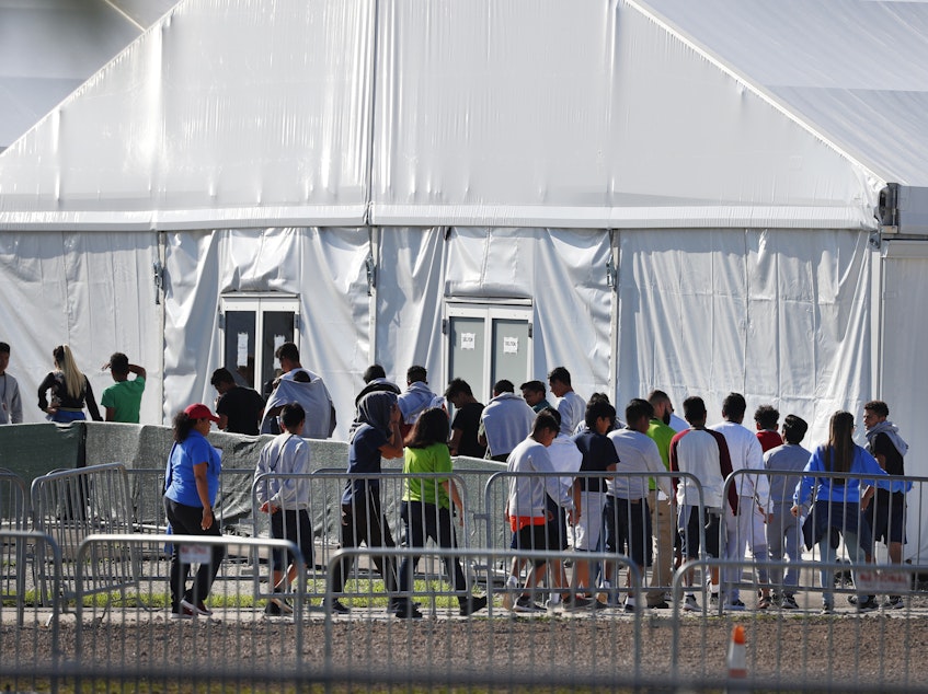 caption: Children line up in February 2018 to enter a tent at the Homestead Temporary Shelter for Unaccompanied Children in Homestead, Fla. Many of these kids were taken from their parents after crossing the border illegally.