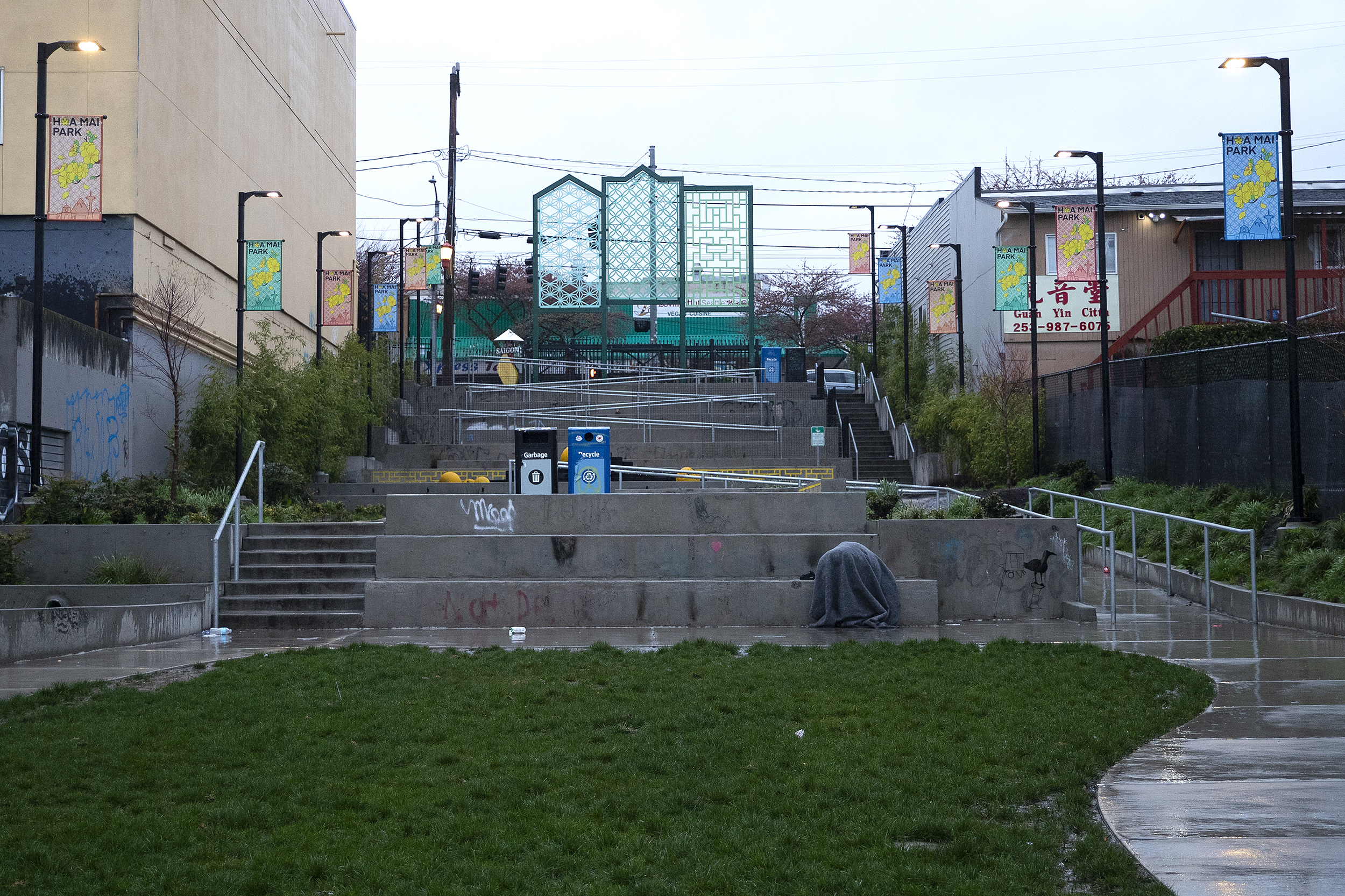 caption: A person is shown under a blanket at Hoa Mai Park on Thursday, March 20, 2025, in Seattle’s Little Saigon neighborhood. 