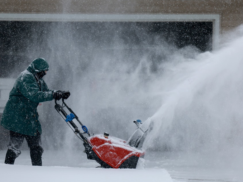 caption: Linda Rae uses a snowblower to clear her driveway during a  snowstorm on Friday in Des Moines, Iowa.