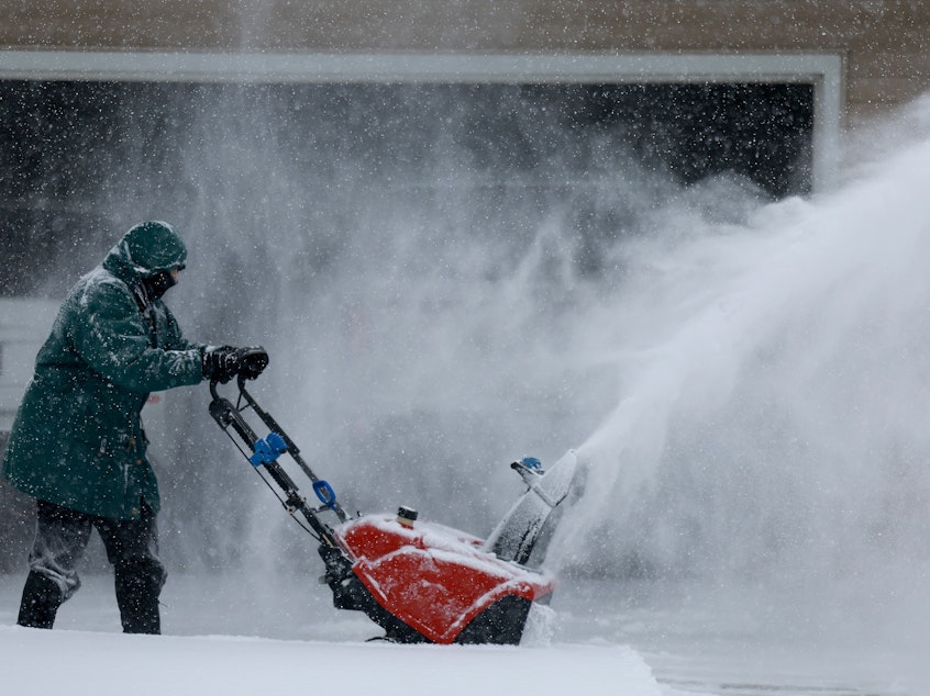 caption: Linda Rae uses a snowblower to clear her driveway during a snowstorm on Friday in Des Moines, Iowa.
