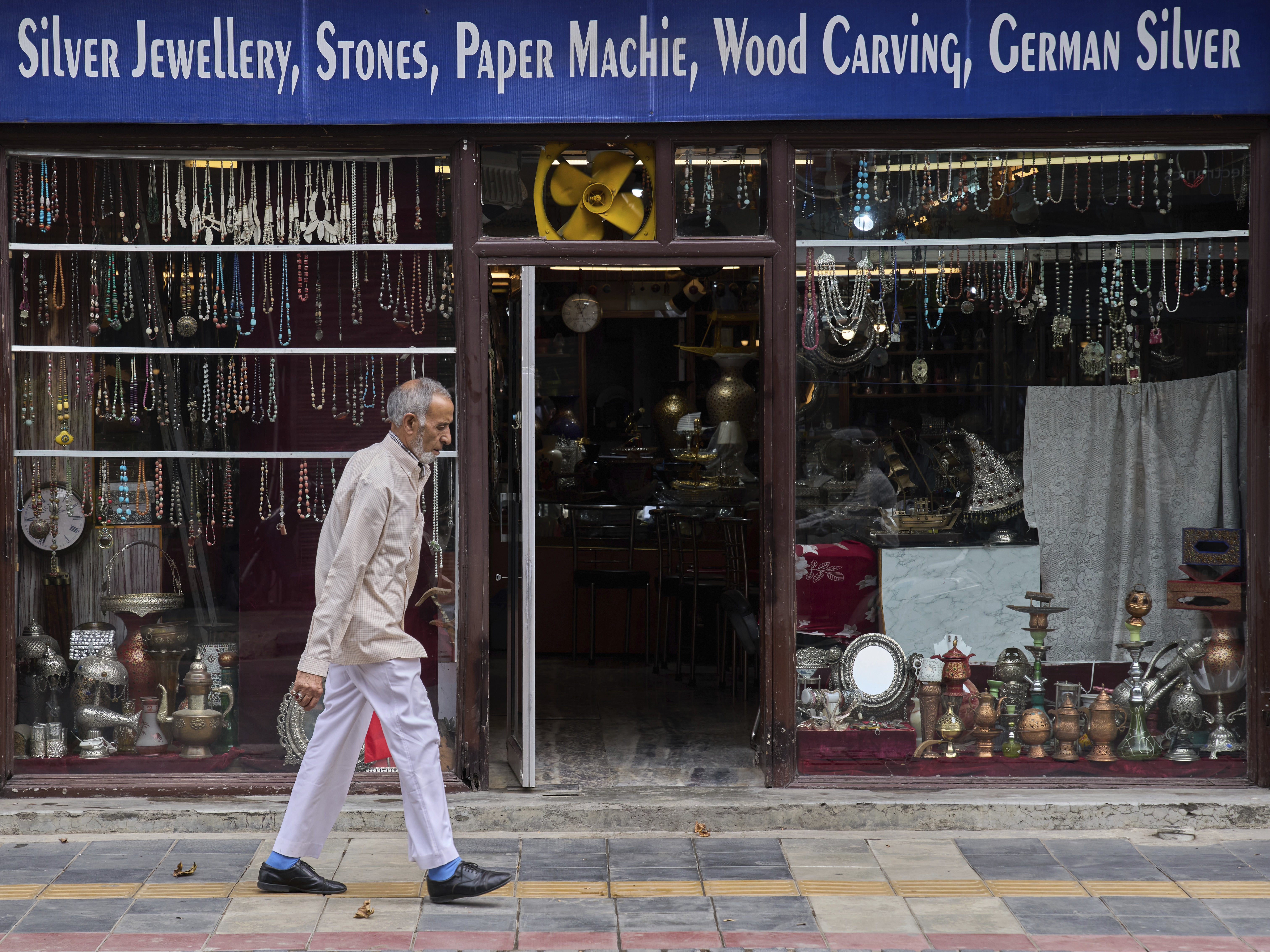 caption: A Kashmiri man walks past a shop displaying stone jewellery and Kashmiri handicrafts in Srinagar, Indian controlled Kashmir.