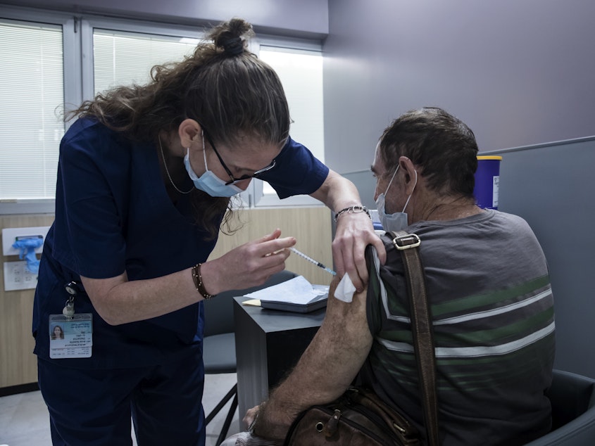caption: A man receives the Pfizer COVID vaccine in Ramat Gan, Israel. A small Israeli study suggests vaccinated people who experience rare breakthrough infections may develop symptoms that last as long as six weeks.