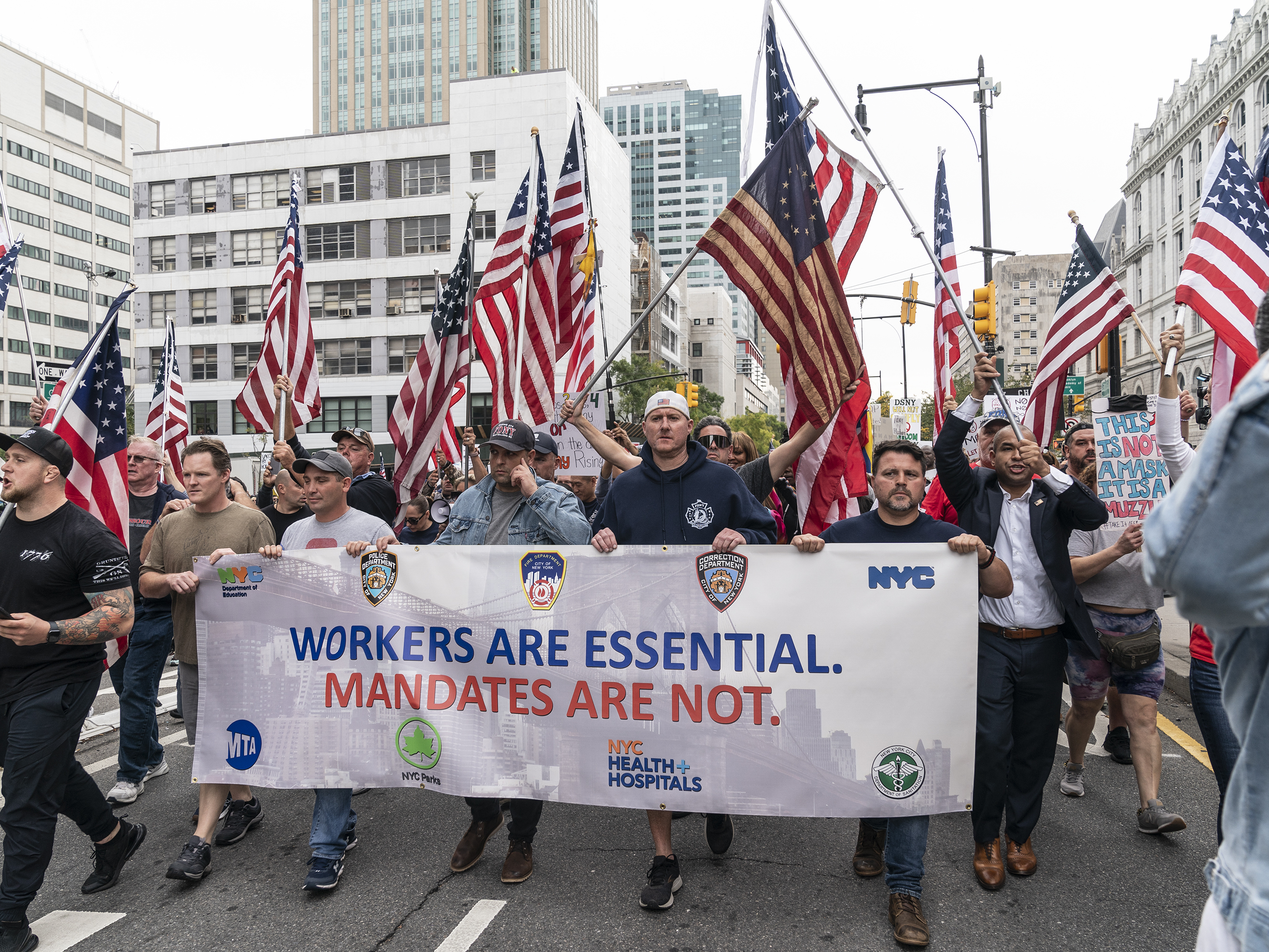 caption: New York city municipal workers, including police officers and firefighters, rally on Monday against a vaccination mandate. City workers are required to get vaccinated against COVID-19 by Nov. 1 or risk losing their jobs.