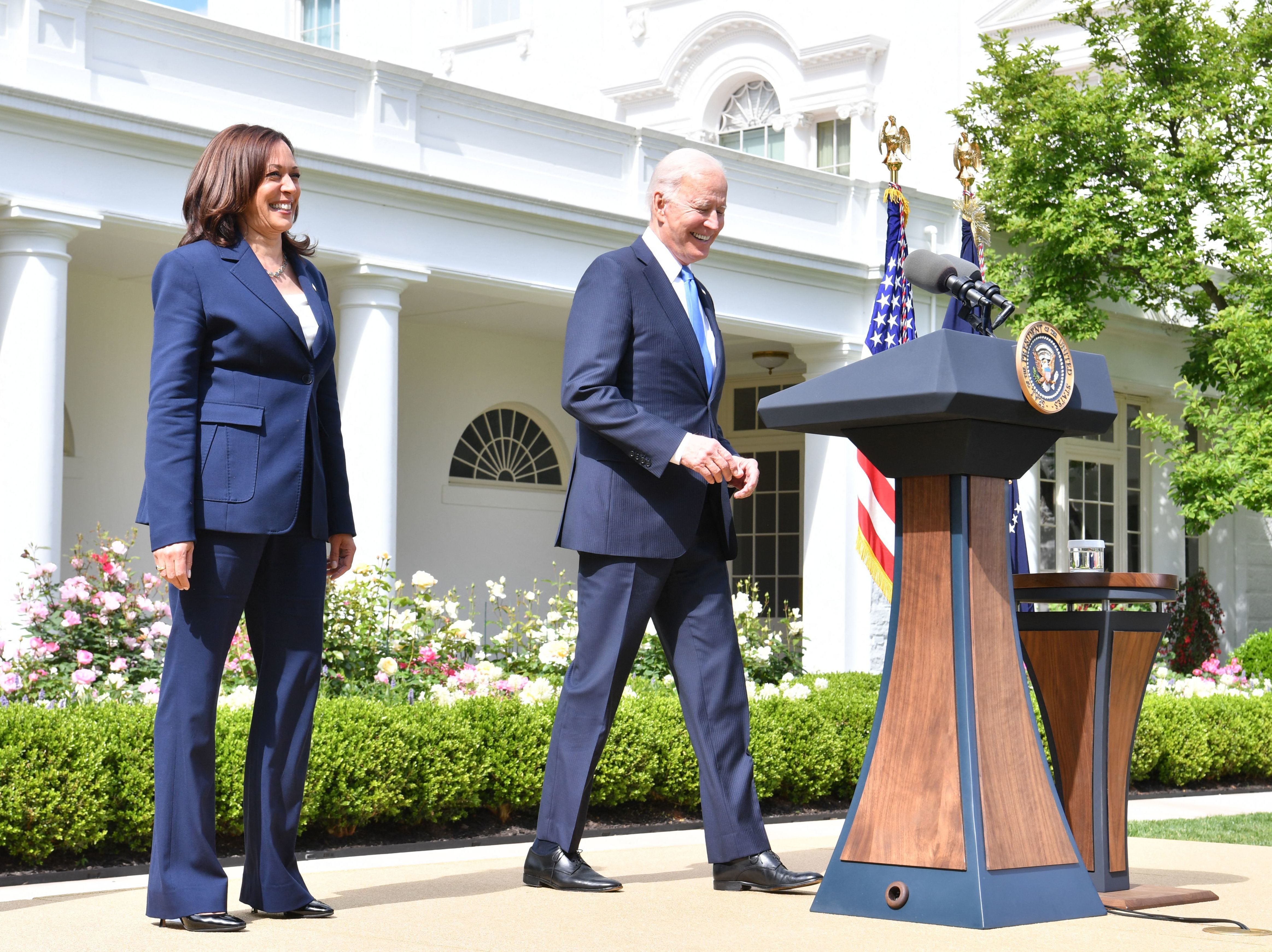 caption: President Biden arrives with Vice President Harris to discuss the CDC's new mask guidance in the Rose Garden of the White House on Thursday.