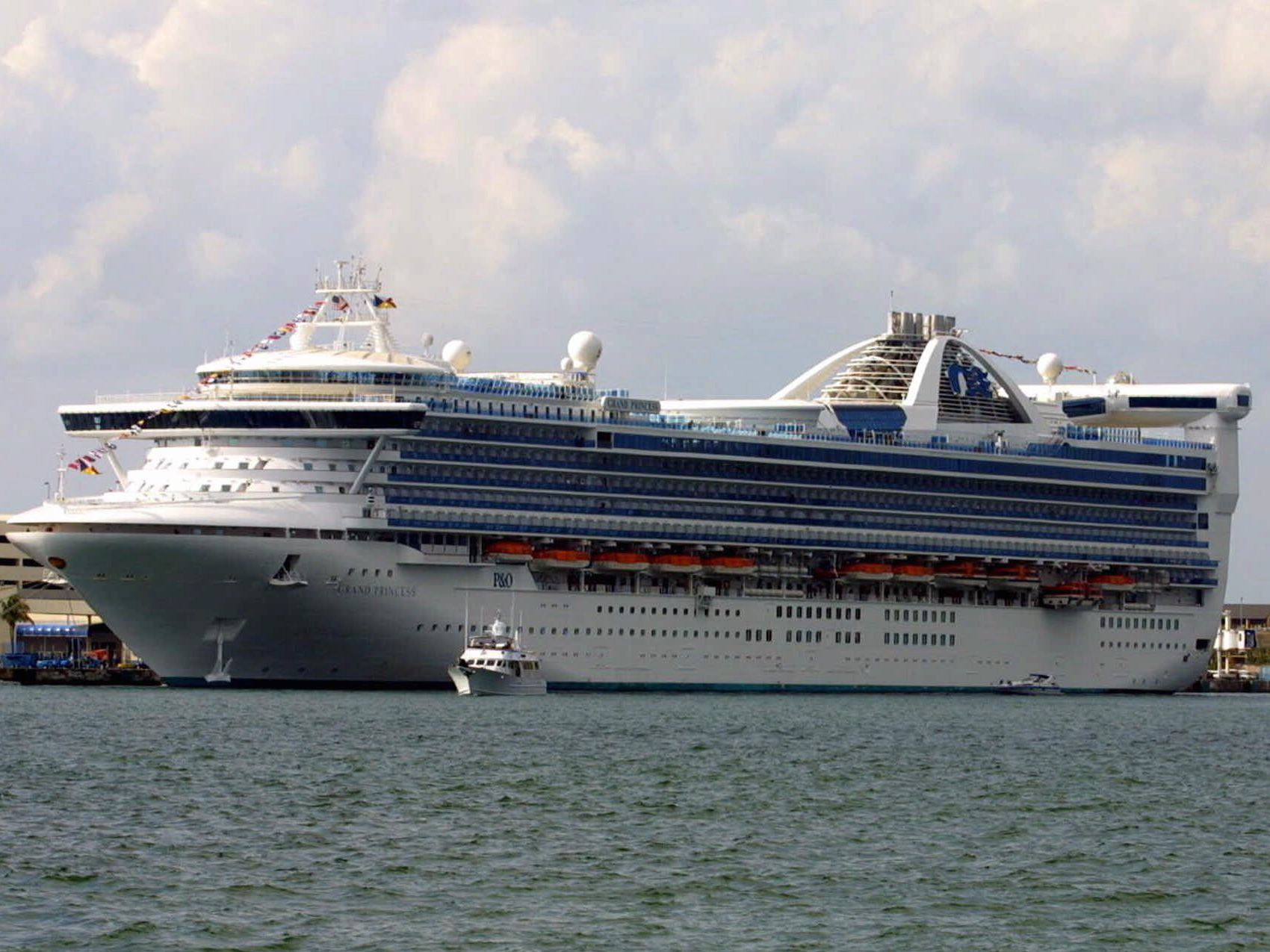 caption: At least 100 people aboard the Grand Princess cruise ship will be tested for the coronavirus that causes COVID-19, after a former passenger died from the disease this week. The ship is seen here in a photo from 2001.