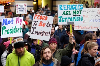 caption: FILE: People begin to gather before a rally protesting President Donald Trump's travel ban on refugees and citizens of seven Muslim-majority nations, Sunday, Jan. 29, 2017, in Seattle. 