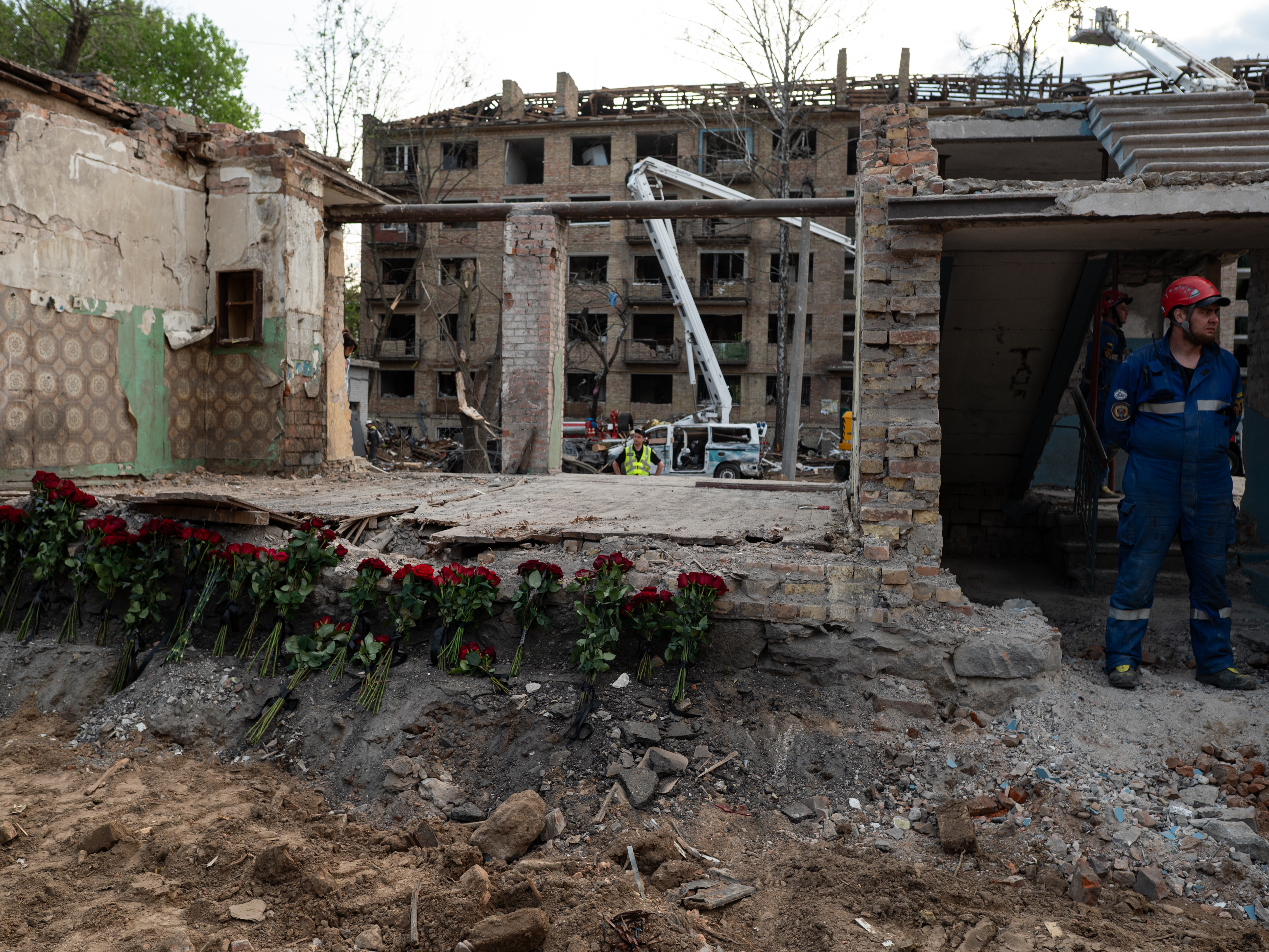 caption: Rescue workers stand near a destroyed building, where roses are placed in Kyiv, Ukraine, in tribute to the victims of the Russian rocket attack the day before, on April 24.