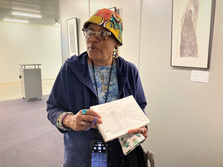 caption: Seattle resident Pam Brown shows a sketch she drew while visiting the "Black Activism in Print" exhibit on July 26, 2023.