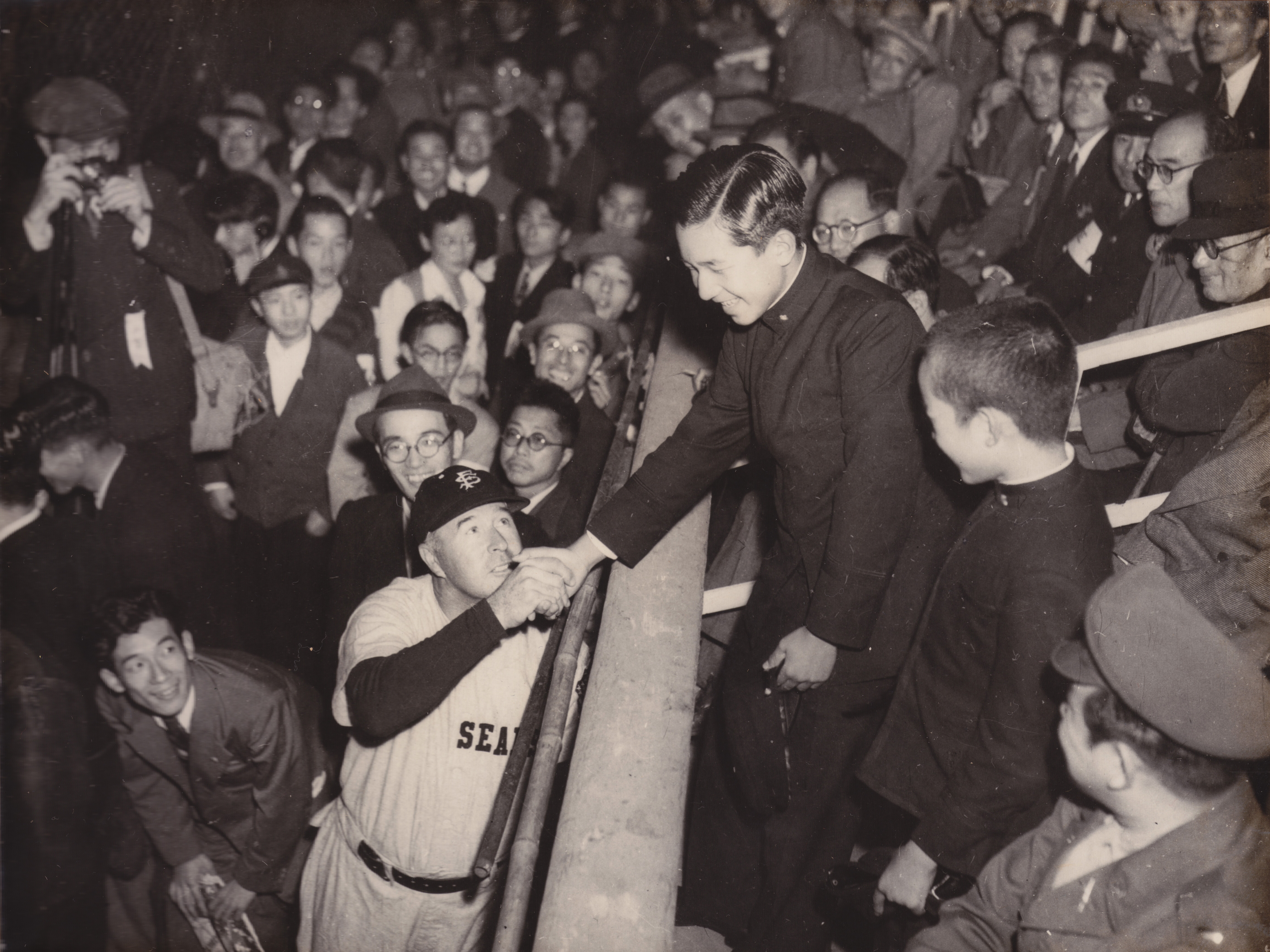 caption: Lefty O'Doul shakes hands with Crown Prince Akihito (at that time future emperor, now abdicated emperor) during the 1949 SF Seals Goodwill Tour to Japan during the Allied occupation.