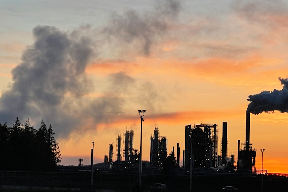 caption: The sun sets behind the Marathon Petroleum refinery in Anacortes in April 2022.