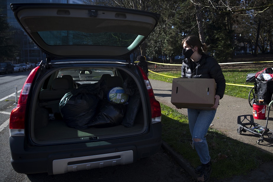 caption: A community member places Robert DeWitt's belongings into their personal vehicle before driving them to another location as Seattle police and Seattle Parks and Recreation sweep unhoused people from Denny Park on Wednesday, March 3, 2021, in Seattle. DeWitt stayed overnight with the hopes of speaking to outreach services but was only approached by police.