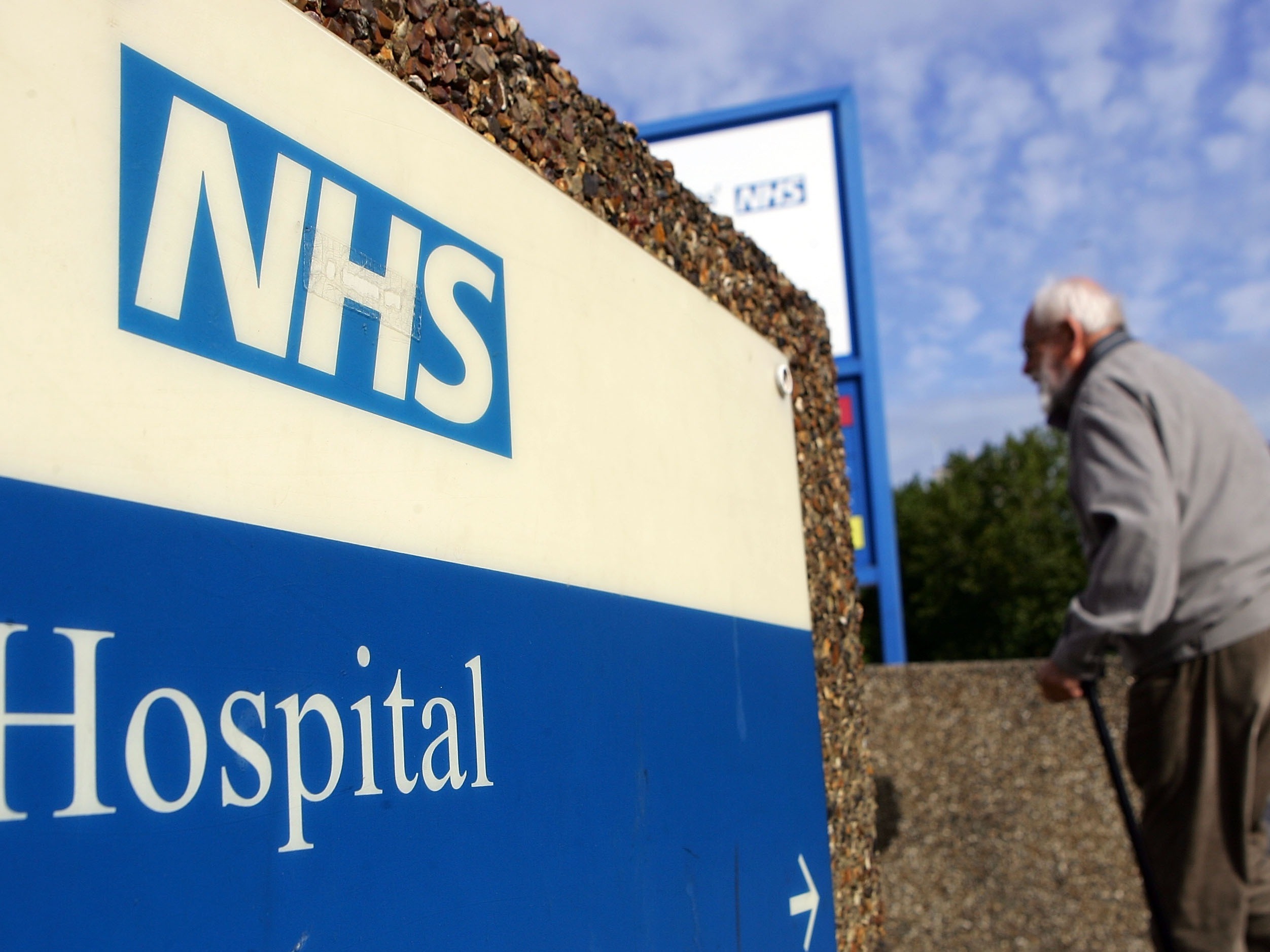 caption: A man walks past a National Health Service sign in 2007 in London. The NHS offers services at the Askern Medical Practice in Doncaster, whose patients mistakenly received text messages informing them of a terminal cancer diagnosis.