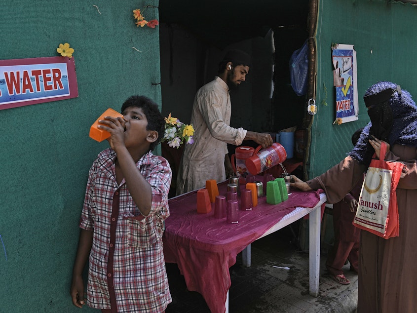 caption: A volunteer distributes drinking water next to a bus stand on a hot summer day in Hyderabad, India, Thursday, March 21, 2024.