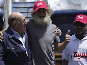 caption: Australian Timothy Lyndsay Shaddock gives a thumbs up during a welcoming ceremony with Grupo Mar President Antonio Suarez, left, and Oscar Meza Oregó, captain of the Mexican tuna boat "Maria Delia," after being rescued from sea and arriving to port in Manzanillo, Mexico, Tuesday, July 18, 2023.