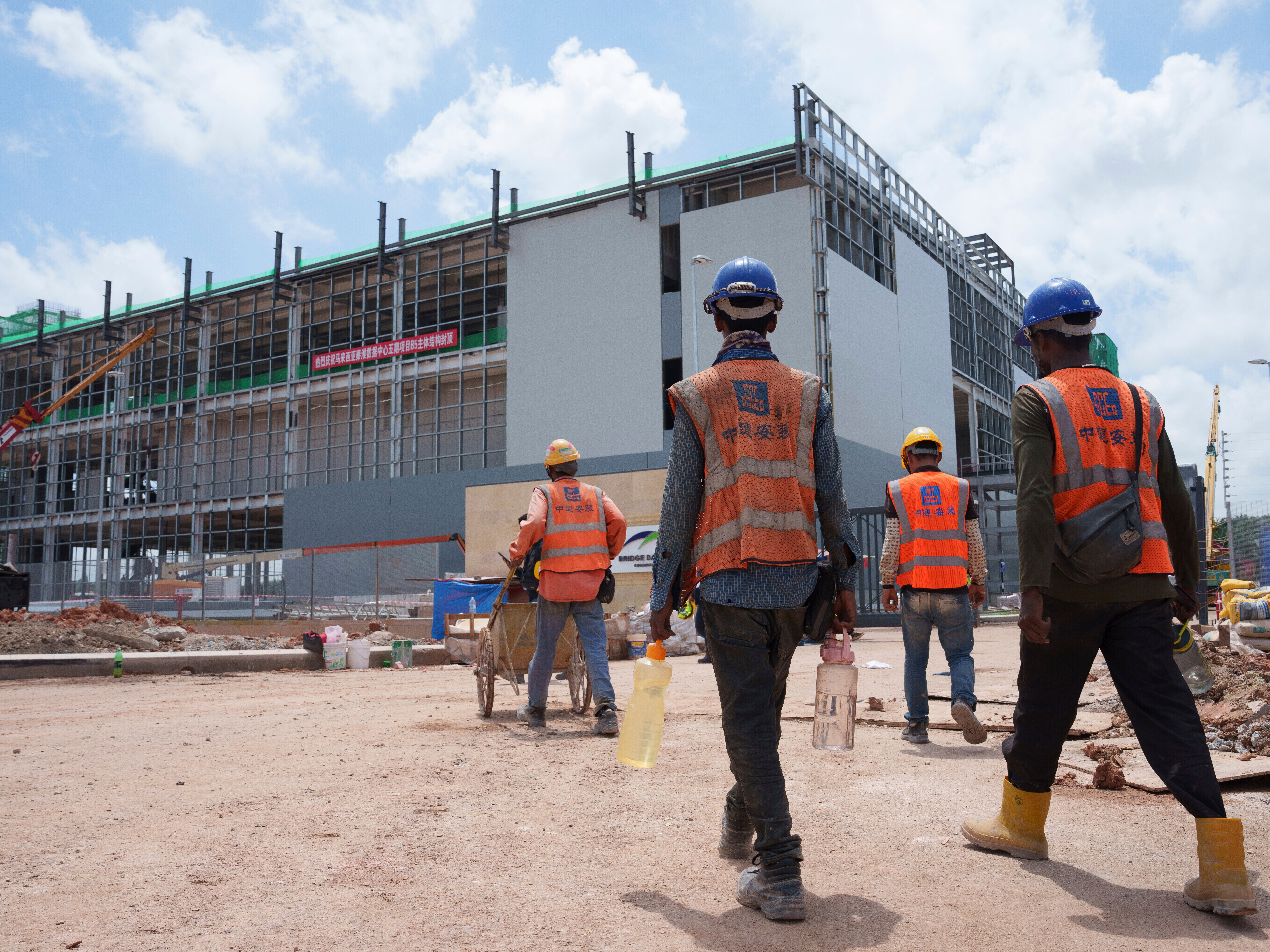 caption: FILE -Construction workers walk to a data center building under construction in Sedenak Tech Park in Johor state of Malaysia, Sept. 27, 2024.