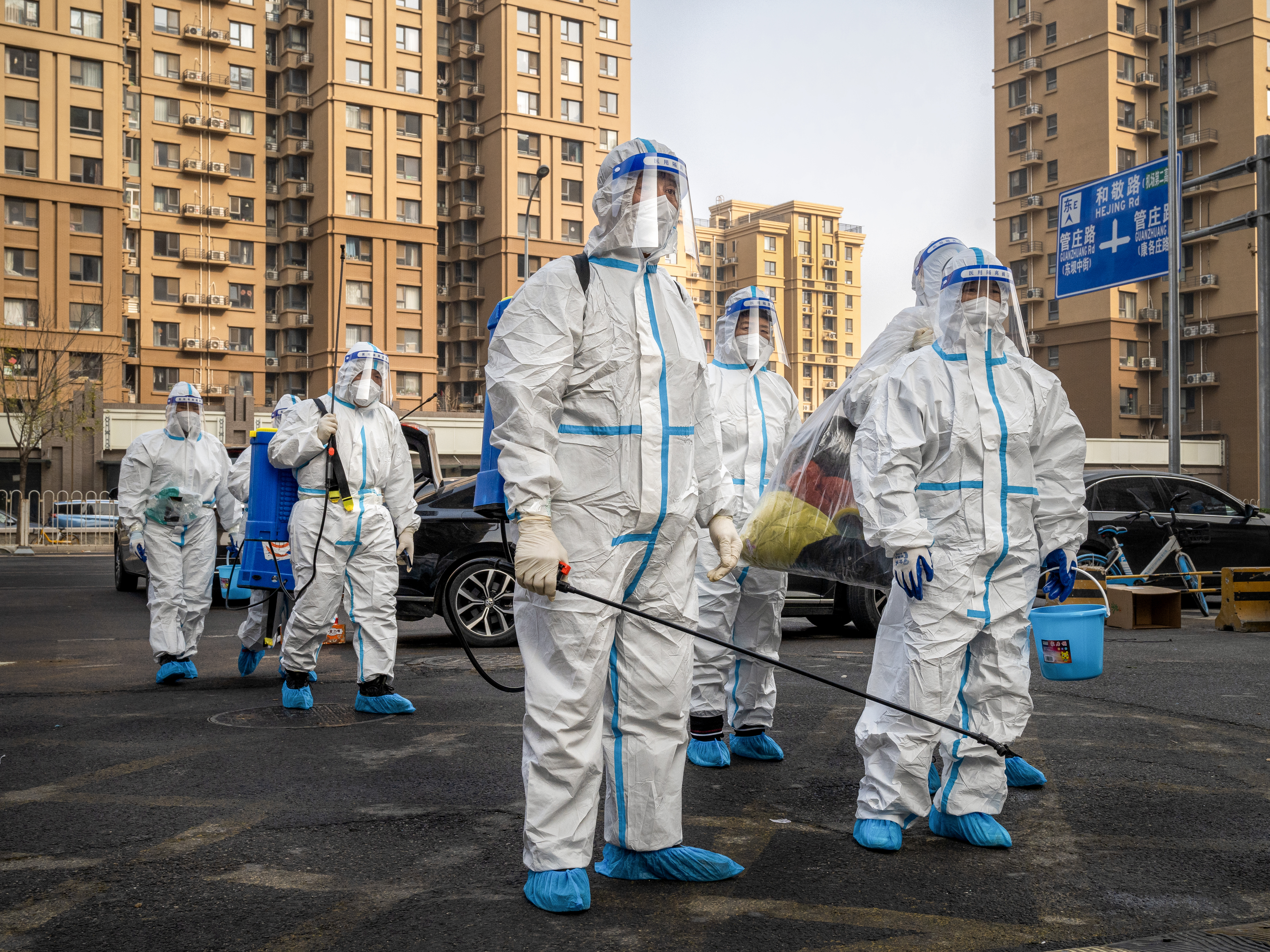 caption: Workers wear protective gear in a Beijing neighborhood placed under lockdown in November. China had raised hopes by slightly relaxing its zero-COVID policy, but cities have been contending with a surge in cases.