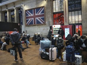 caption: Passengers wearing face masks wait next to the Eurostar Terminal at Gare du Nord train station in Paris on Monday. France is banning all travel from the U.K. for 48 hours in an attempt to make sure that a new strain of the coronavirus in Britain doesn't reach its shores.