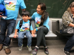 caption: Christine Vega and her 5-year-old son Gibson ride the underground tram to get to their practice terminal.