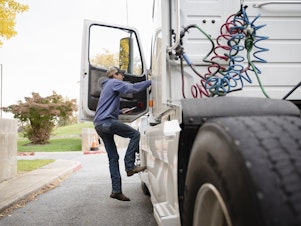 caption: Tucker Bubacz, a 17-year-old senior, climbs into the cab of a semi truck just outside Williamsport High School in Williamsport, Md. on Monday, Oct. 17, 2022.