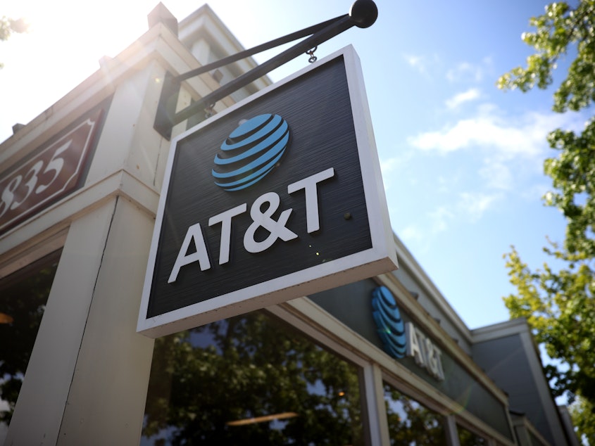 caption: A sign is posted in front of an AT&T retail store in 2021 in San Rafael, Calif.