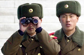 caption: A North Korean soldier looks at the southern side through a pair of binoculars at the border village of Panmunjom, north of Seoul, Wednesday, Feb. 26, 2003.