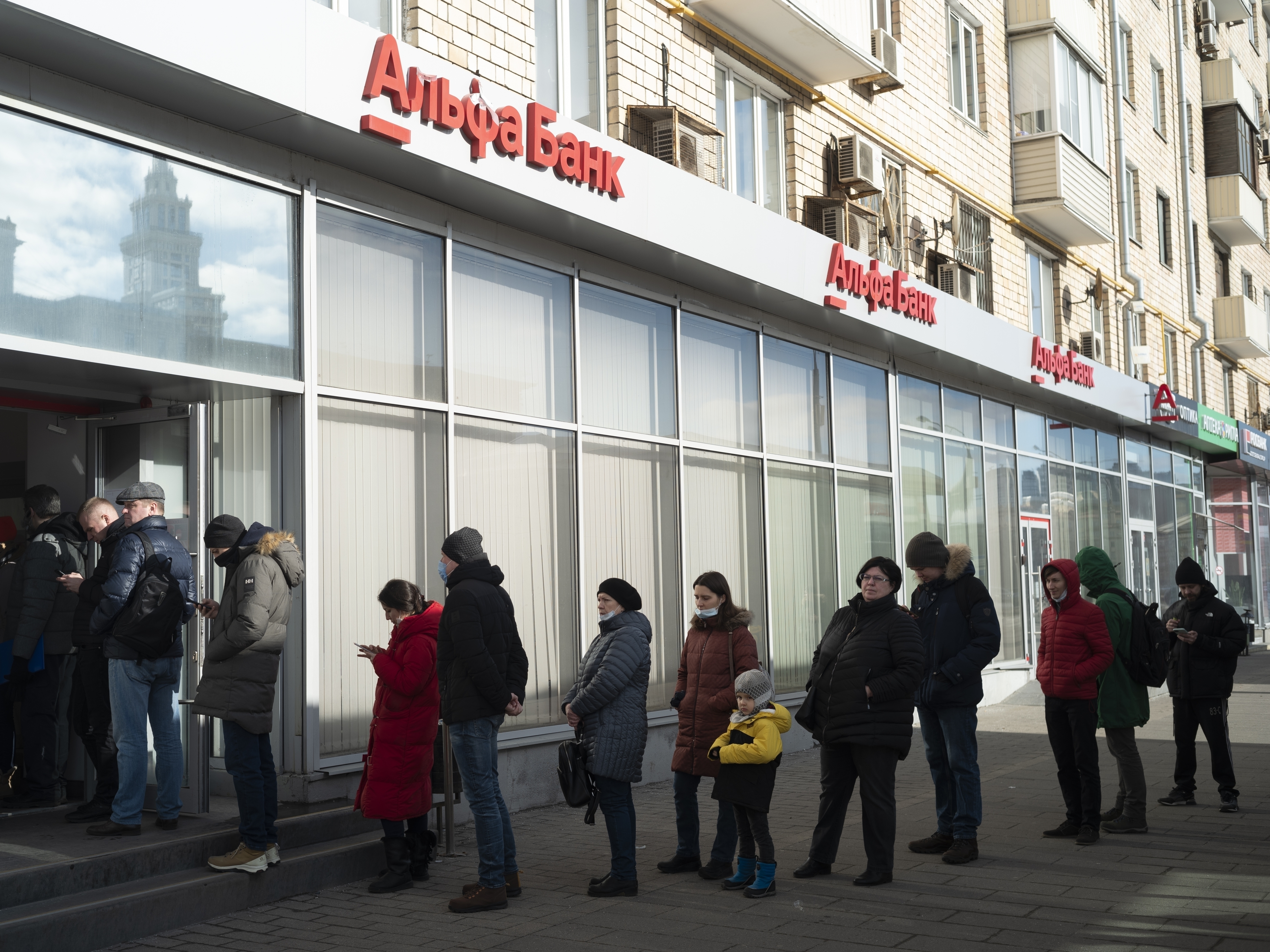 caption: People stand in line to withdraw money from an ATM of Alfa Bank in Moscow on Sunday. Russians flocked to banks and ATMs shortly after Russia launched an attack on Ukraine and the West announced severe sanctions.