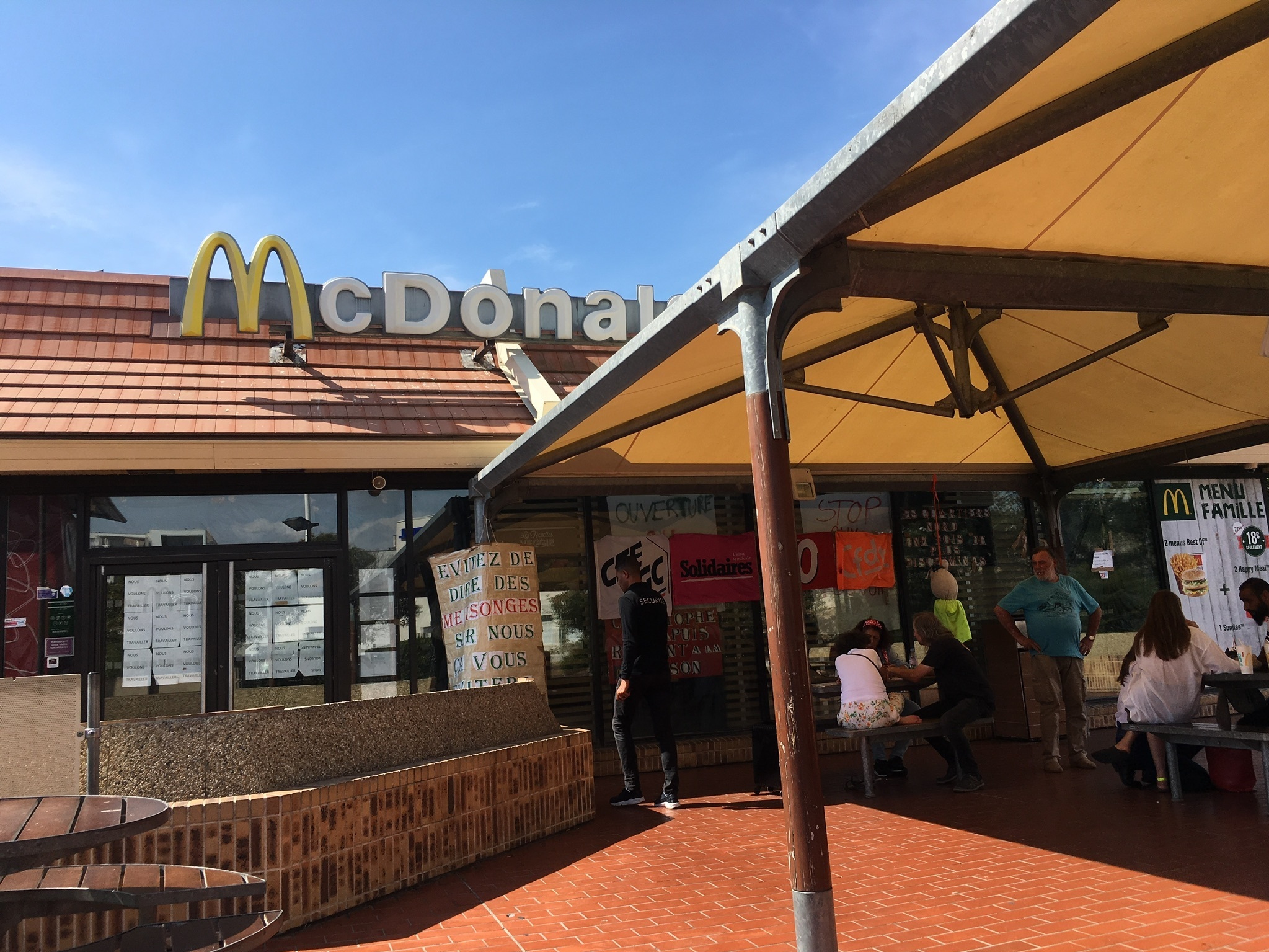 caption: Residents of an immigrant neighborhood in northern Marseille gather outside of a McDonald's they are fighting to keep open.