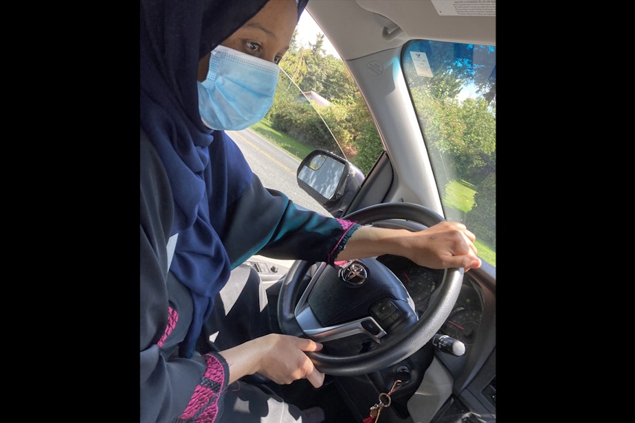 caption: My mom, Mulki Mohamed, wears her mask as she drives me to the grocery store. As she makes a right turn she tells me what we need from the grocery store and to not touch my face when I’m in the store.