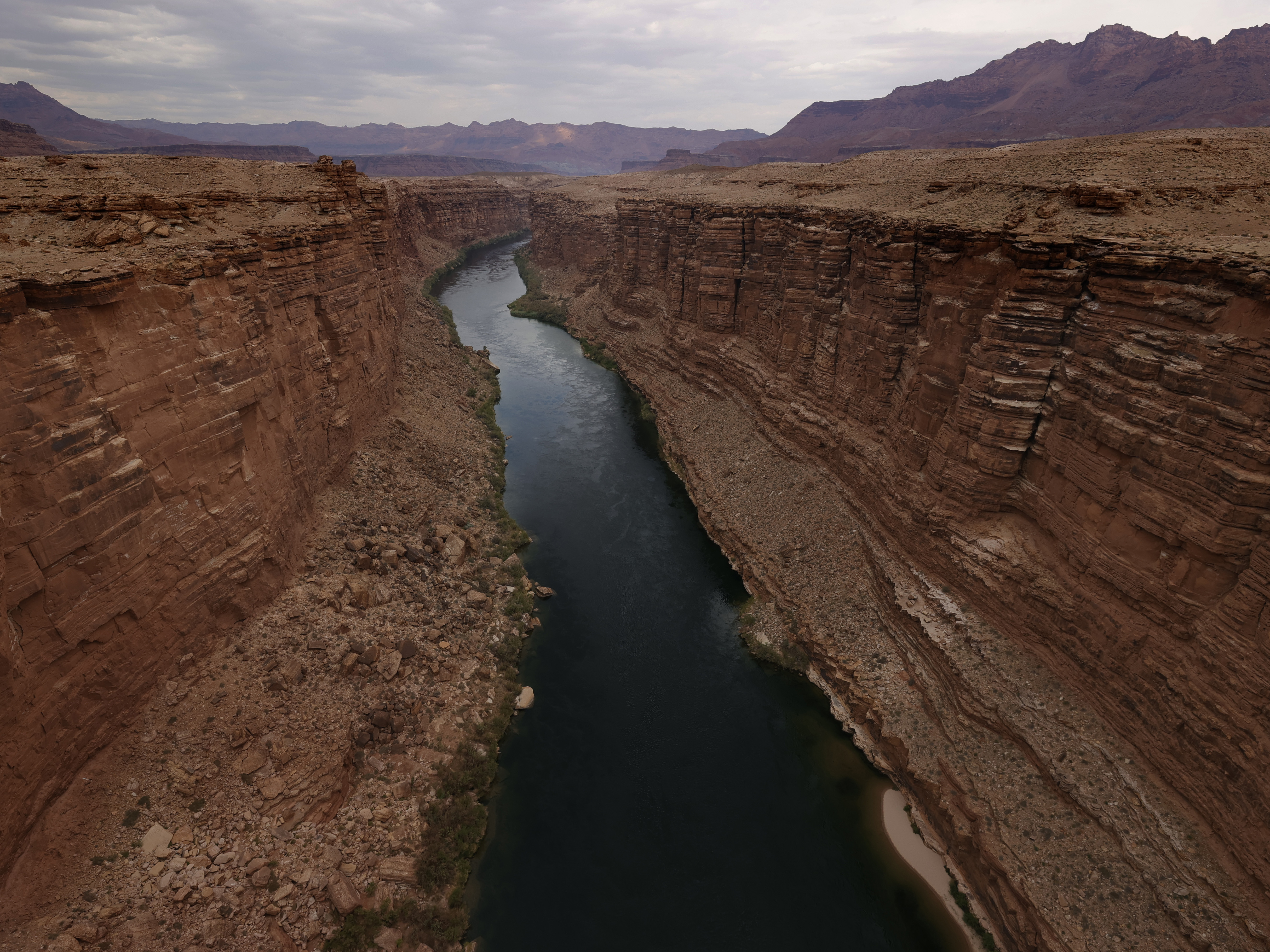 caption: The Colorado River flows by the historic Navajo Bridge on June 23, 2021 in Marble Canyon, Ariz.