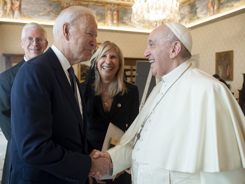 caption: President Biden shakes hands with Pope Francis as they meet at the Vatican on Friday.