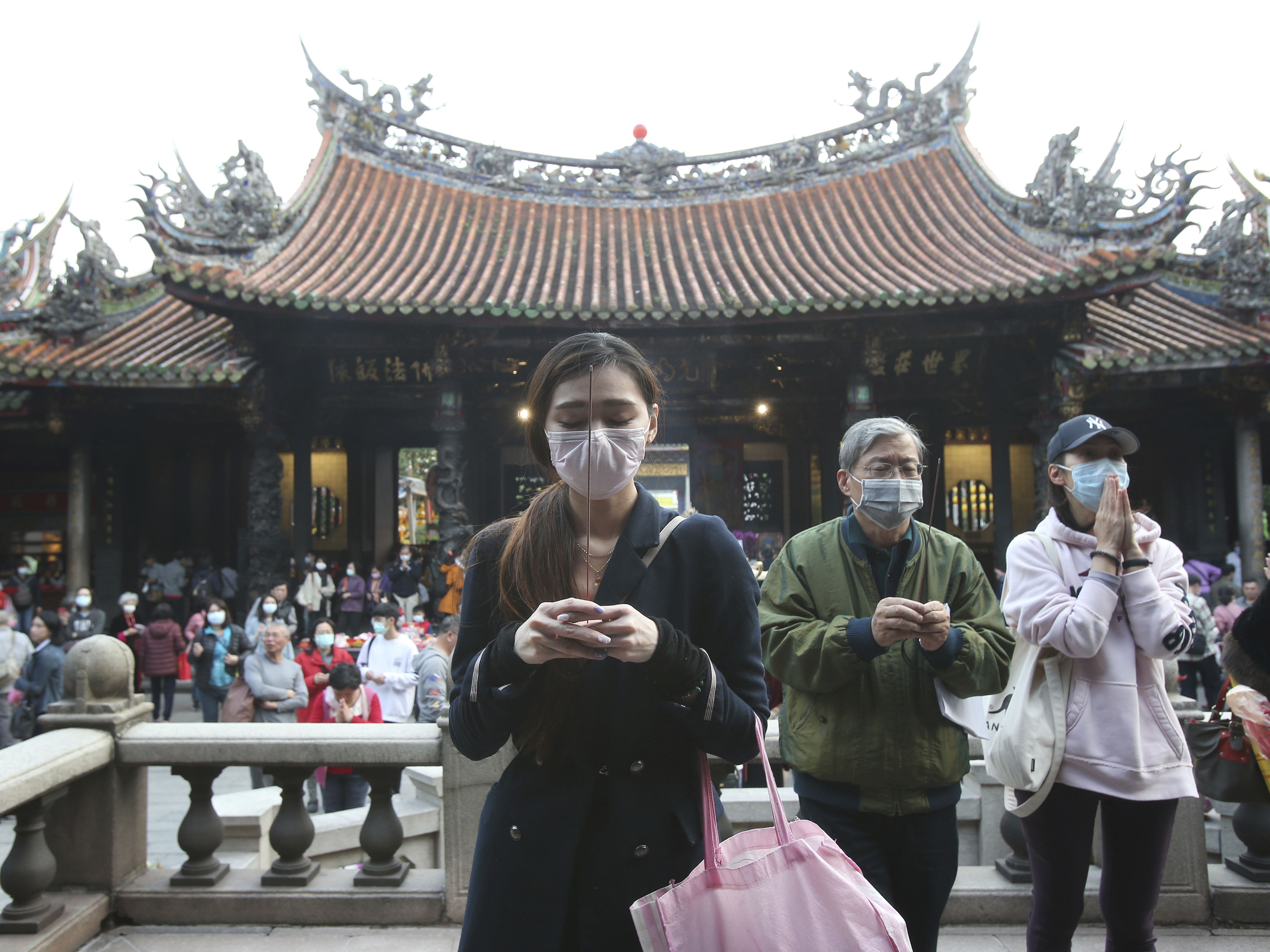 caption: People wear face masks to protect against the spread of the coronavirus as they pray at the Longshan Temple in Taipei, Taiwan, on Thursday. Taiwan has reported a relatively low number of cases of the virus despite its proximity to China, where the virus was first detected.