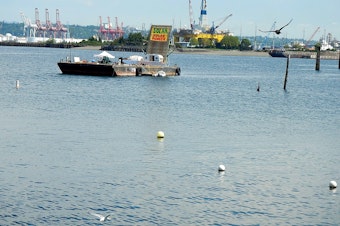 caption: The Solar Pioneer protest barge in Elliot Bay with the Shell oil drilling rig in the background.