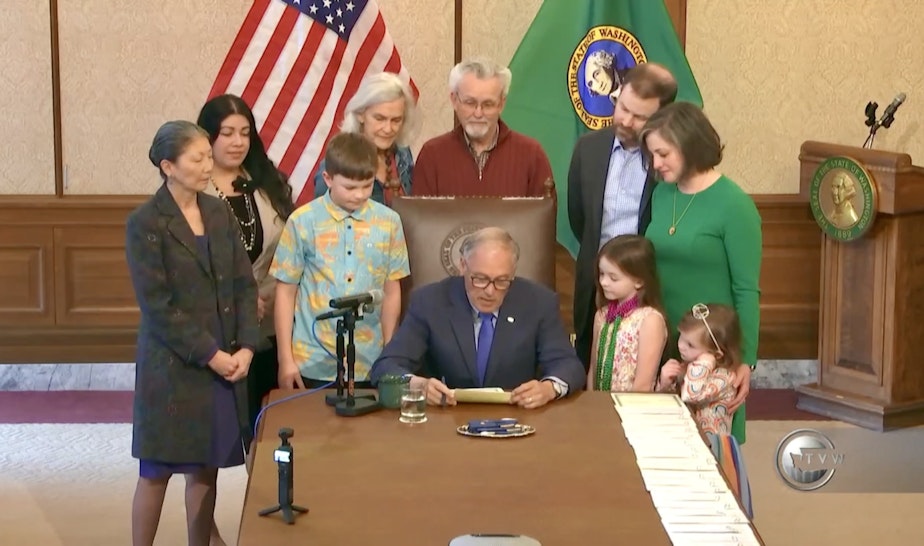 caption: Washington Gov. Inslee signs HB 1239 into law with the Rigg Hillard family and Rep. Santos on March 25, 2024.