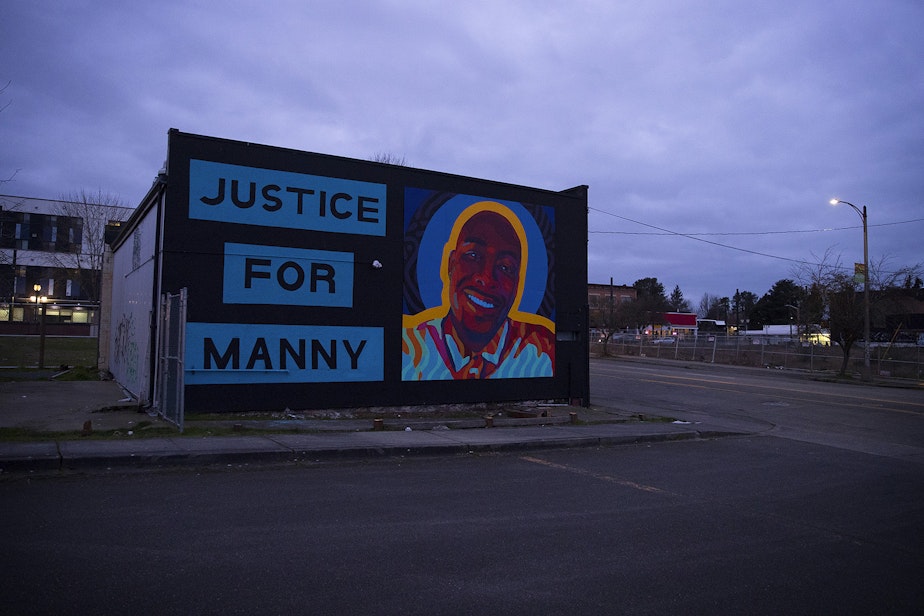 caption: A mural honoring 33-year-old Manuel Ellis is shown as the sun goes down on Sunday, February 28, 2021, near the intersection of Martin Luther King Jr. Way and South 11th Street following a silent march honoring him in Tacoma. “We want to make sure that Bob Ferguson knows that Tacoma does not forget trespasses against us,” said Jamika Scott, with the Tacoma Action Collective, to the crowd at People’s Park.“We won’t forget Manny Ellis,” said Scott. 