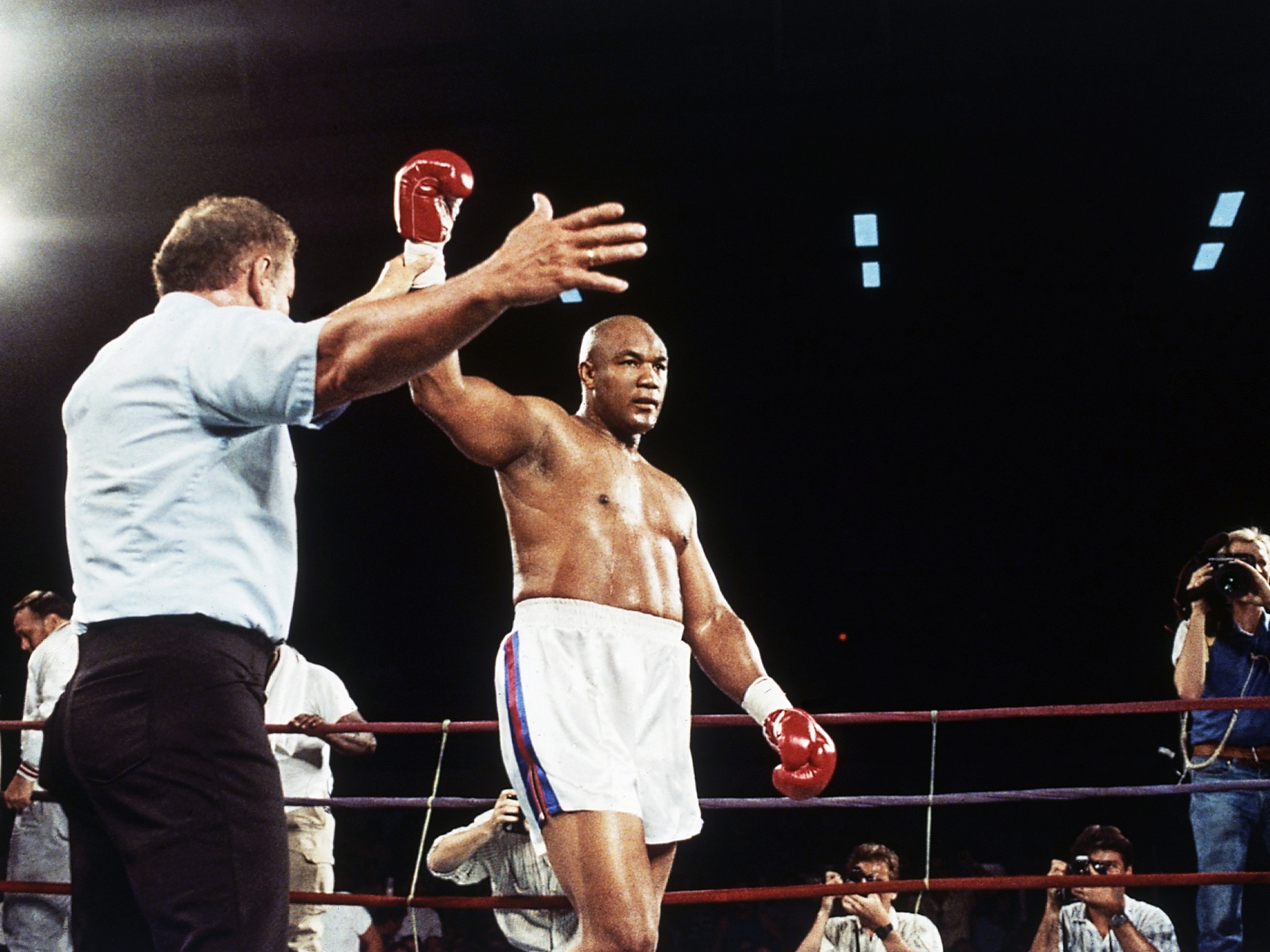 caption: Former heavyweight champion George Foreman has hit glove lifted into the air after referee Al Munoz gave Foreman the victory in his heavyweight fight against Bert Cooper in Phoenix, on June 2, 1989.