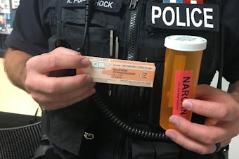 caption: A Bellevue police officer displays a dose of overdose reversal drug, naloxone. 