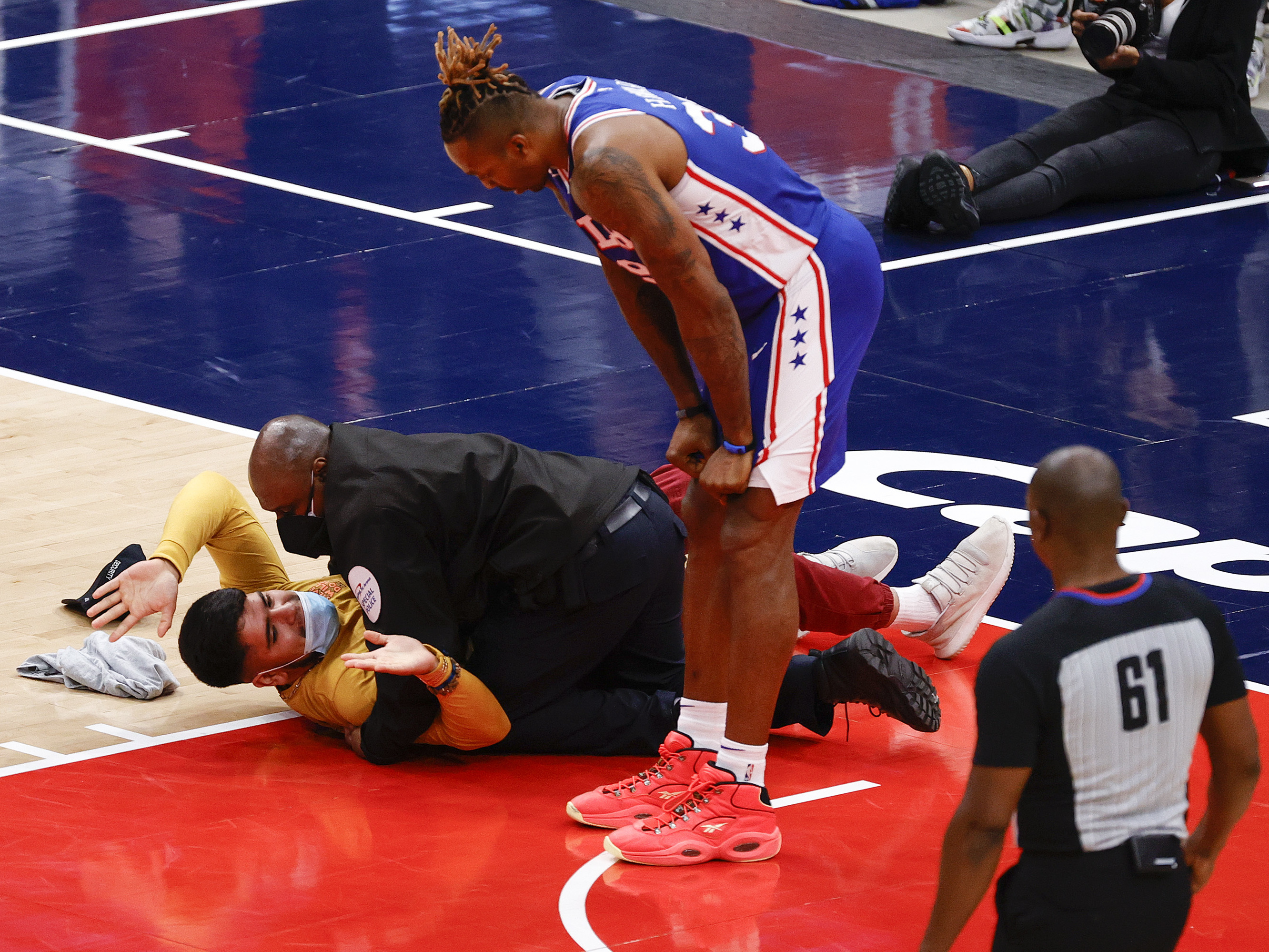 caption: Dwight Howard of the Philadelphia 76ers looks down at a fan who ran onto the court and was tackled by security in Game Four of the Eastern Conference first round series against the Washington Wizards on Monday.
