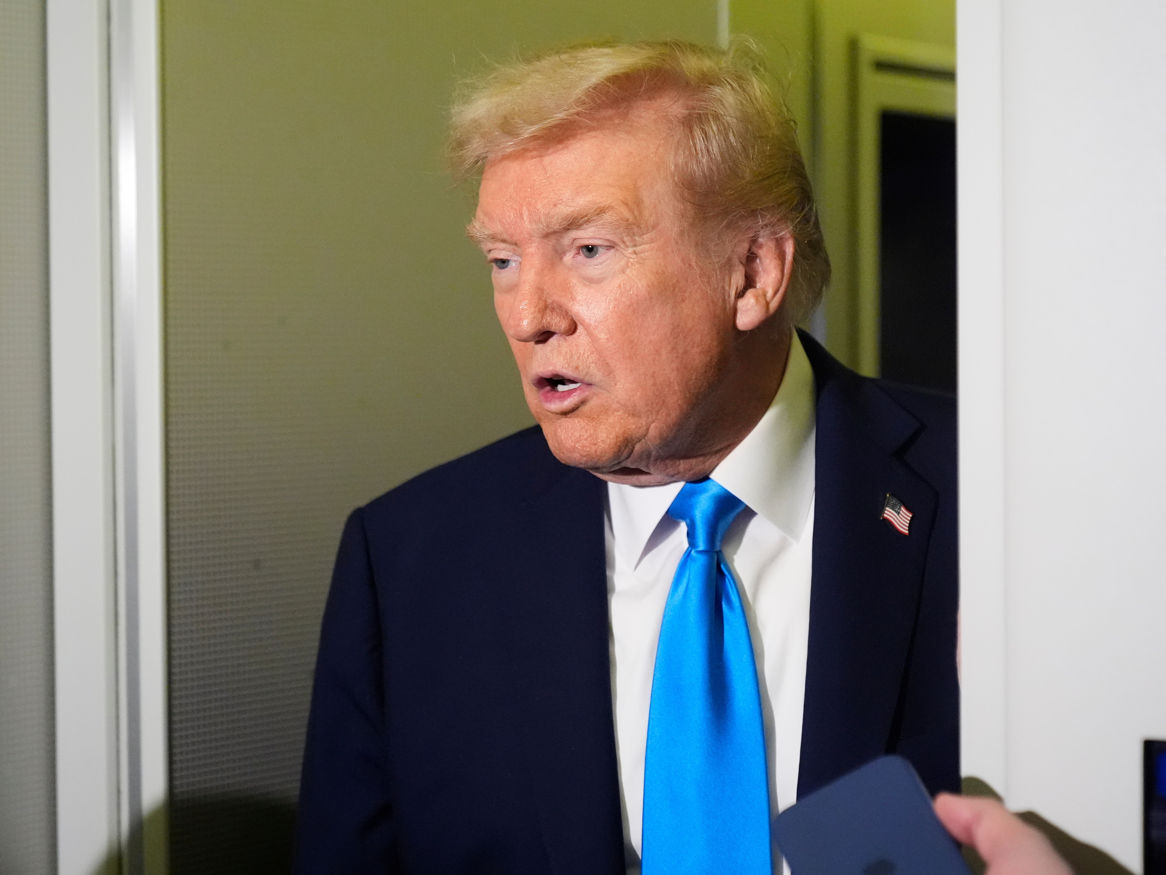 caption: President Trump speaks with reporters aboard Air Force One at Al Udeid Air Base in Doha, Qatar, on Saturday, Oct. 25, 2025.