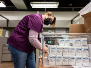 caption: Janet Gerber, a health department worker in Louisville, Ky., processes boxes containing vials of the Johnson & Johnson COVID vaccine in March.