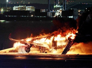 caption: A Japan Airlines jet burst into flames after colliding with a Japanese coast guard plane at Tokyo's Haneda Airport in January. All 379 people on board the Japan Airlines flight were safely evacuated, but the incident raised questions about evacuation standards.