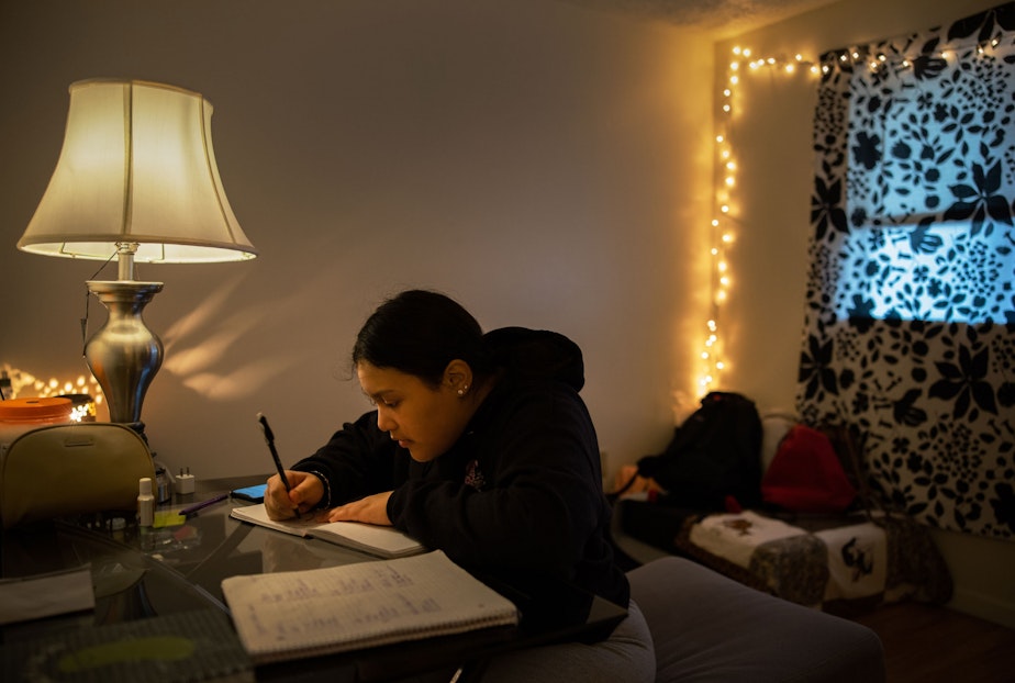 caption: Michelle Aguilar Ramirez works on her daily journaling which she uses to help her reflect and process her life, in her room in Spokane, Washington.