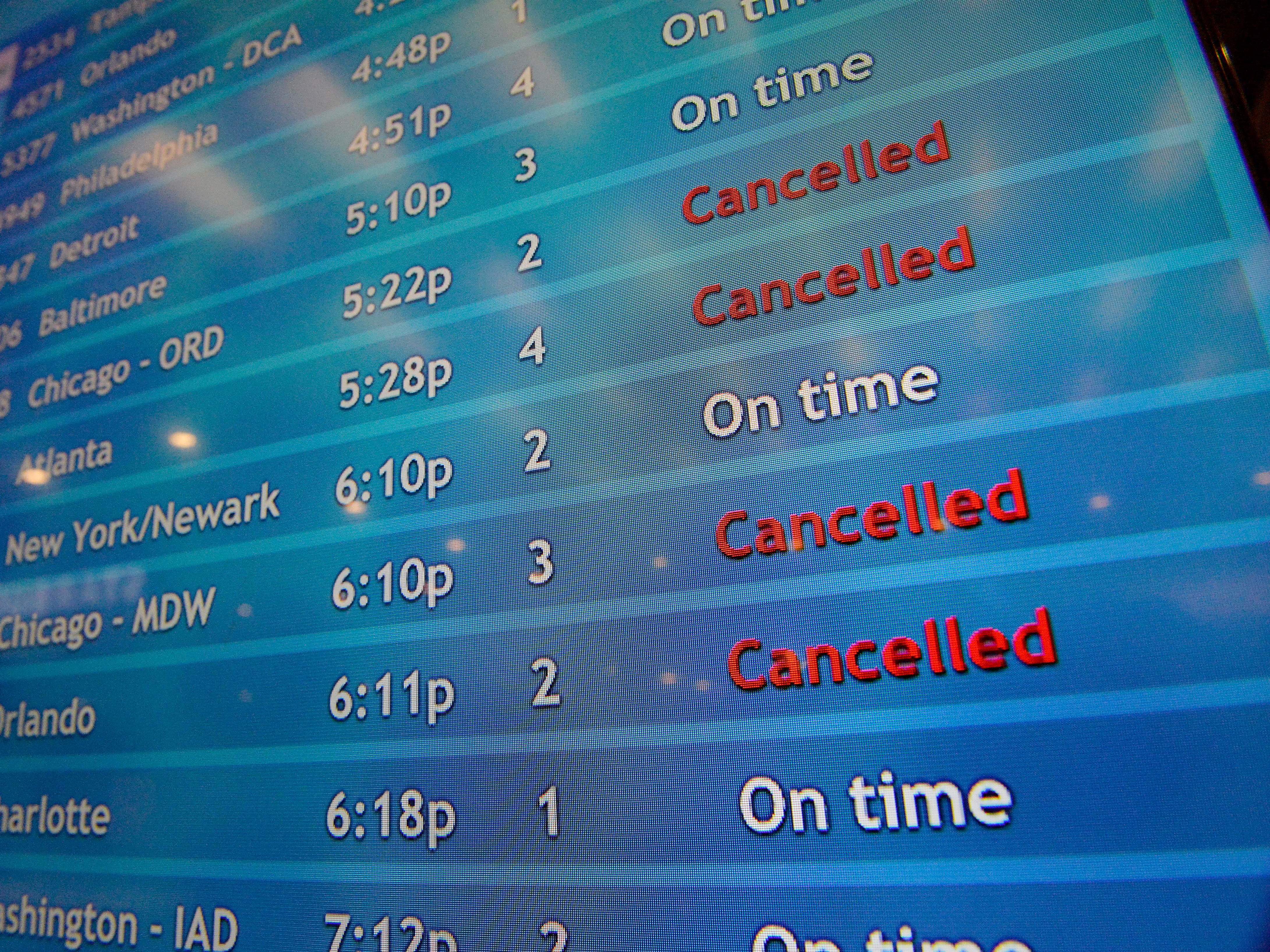 caption: A screen shows canceled incoming flights at TF Green International Airport in Warwick, R.I. on March 30, 2020, during the novel coronavirus outbreak.