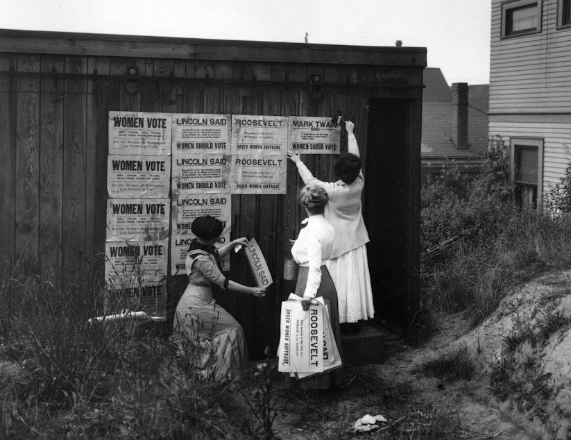 caption:  Three women from the Washington Equal Suffrage Association posting signs in Seattle in 1910.
