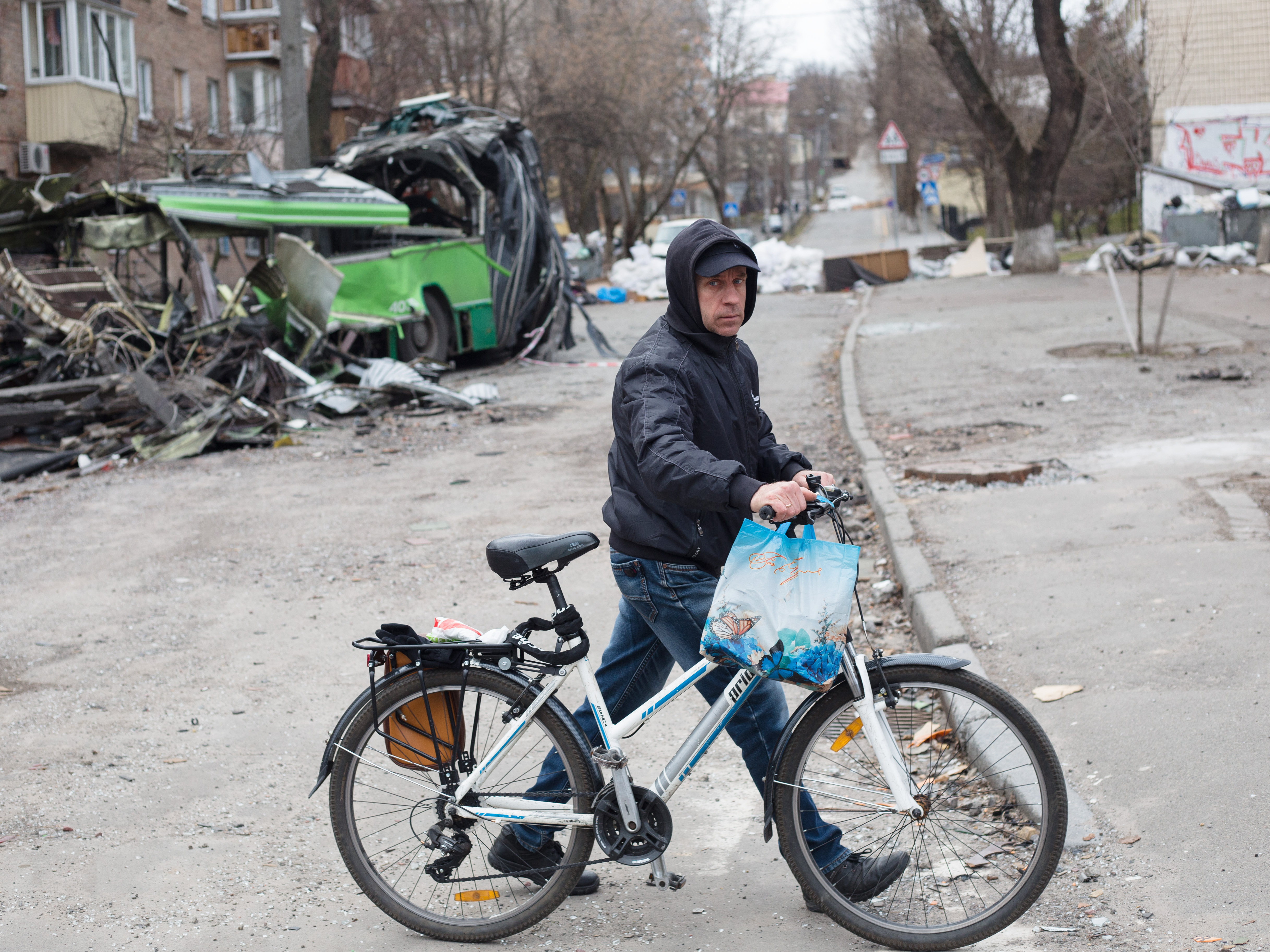 caption: A man with a bicycle walks near a tram which got destroyed by a rocket strike in the area few weeks ago on Monday in Kyiv, Ukraine.