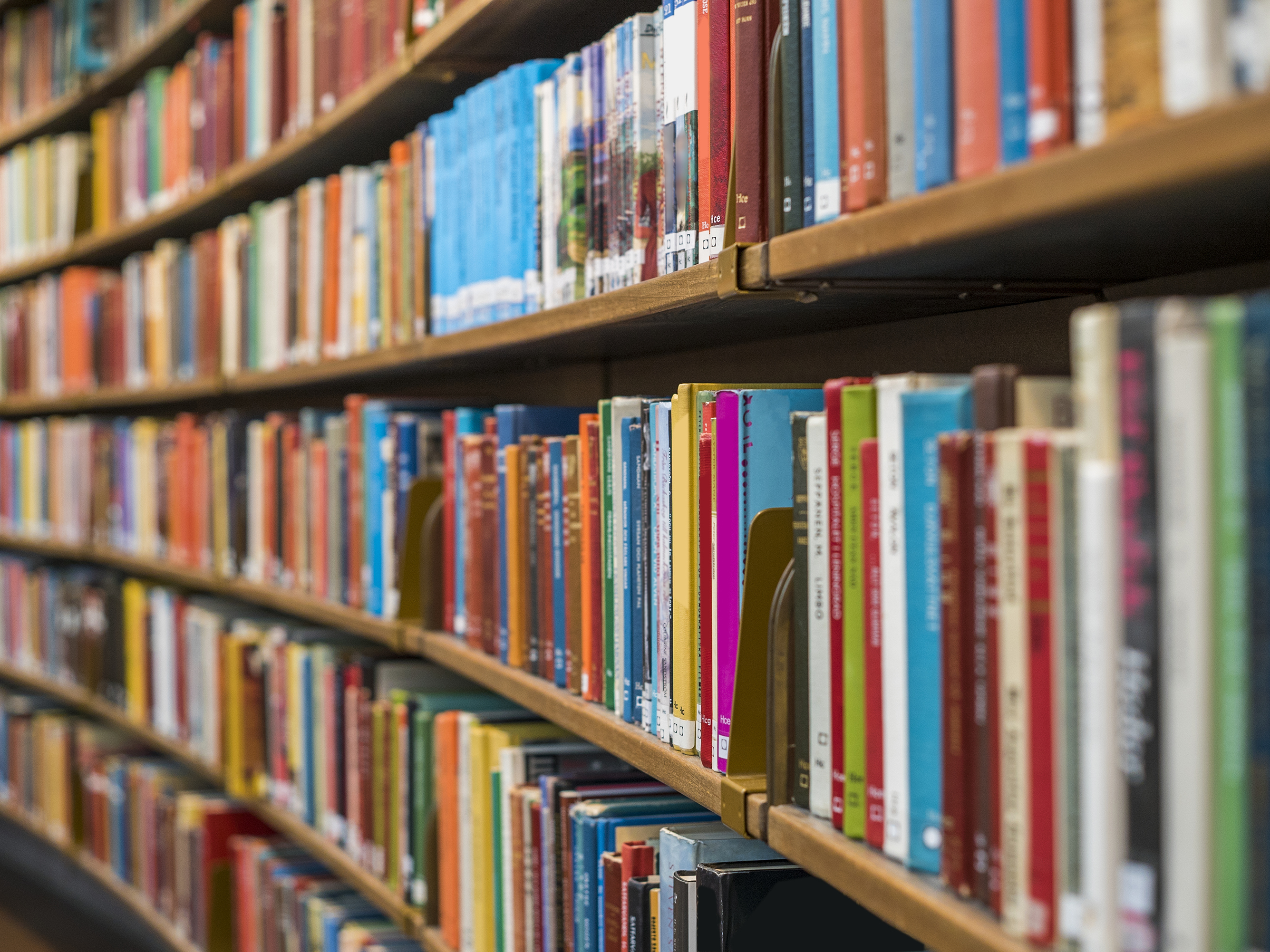 A wall of shelves filled with colorful books in a library.